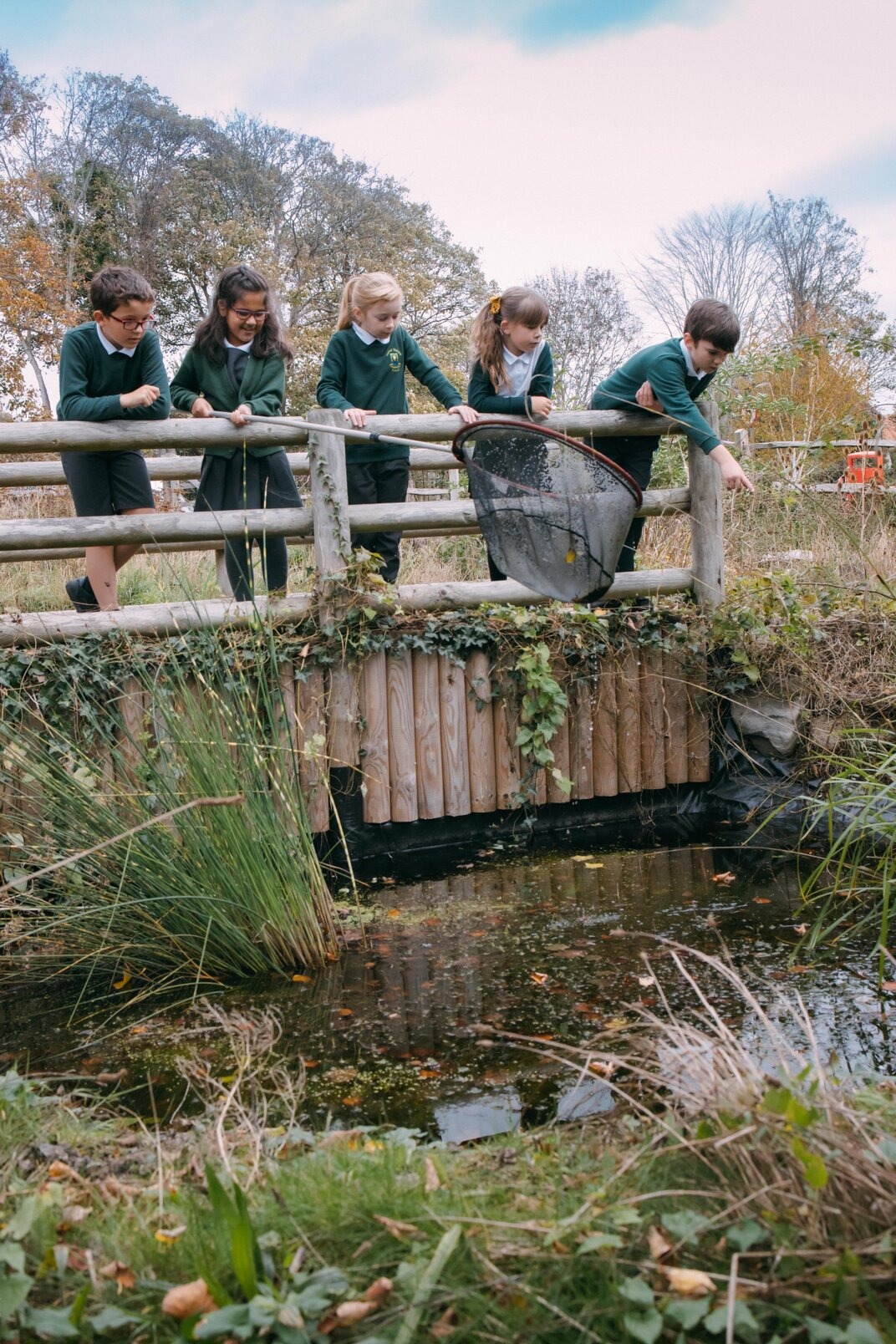 Children on a bridge over a pond with a net