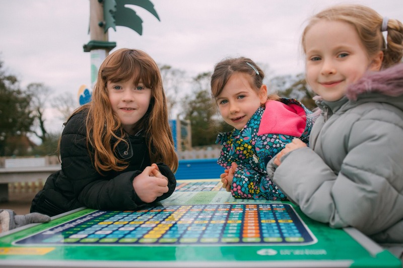 Three girls playing a board game outside